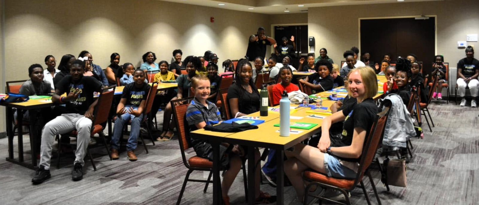 A room full of smiling students seated at tables during a Polished, Poised, and Prepared for Success workshop